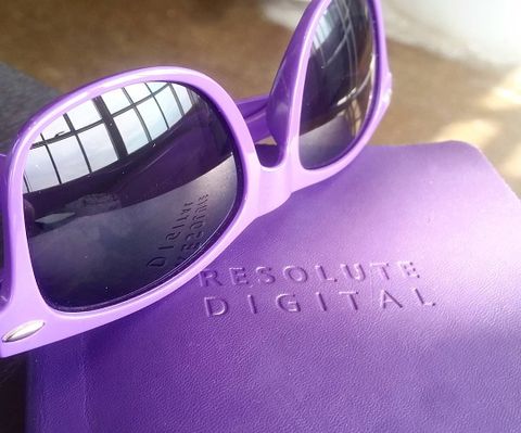 Resolute branded sunglasses resting on purple branded notebook
