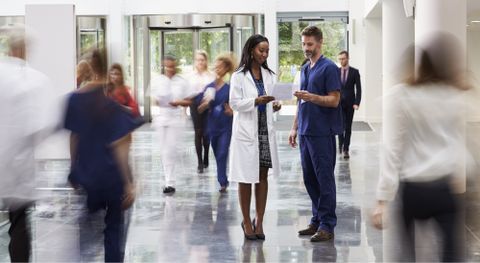 Woman in lab coat in busy hospital lobby