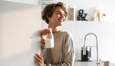 Woman holding a glass bottle of milk in a kitchen