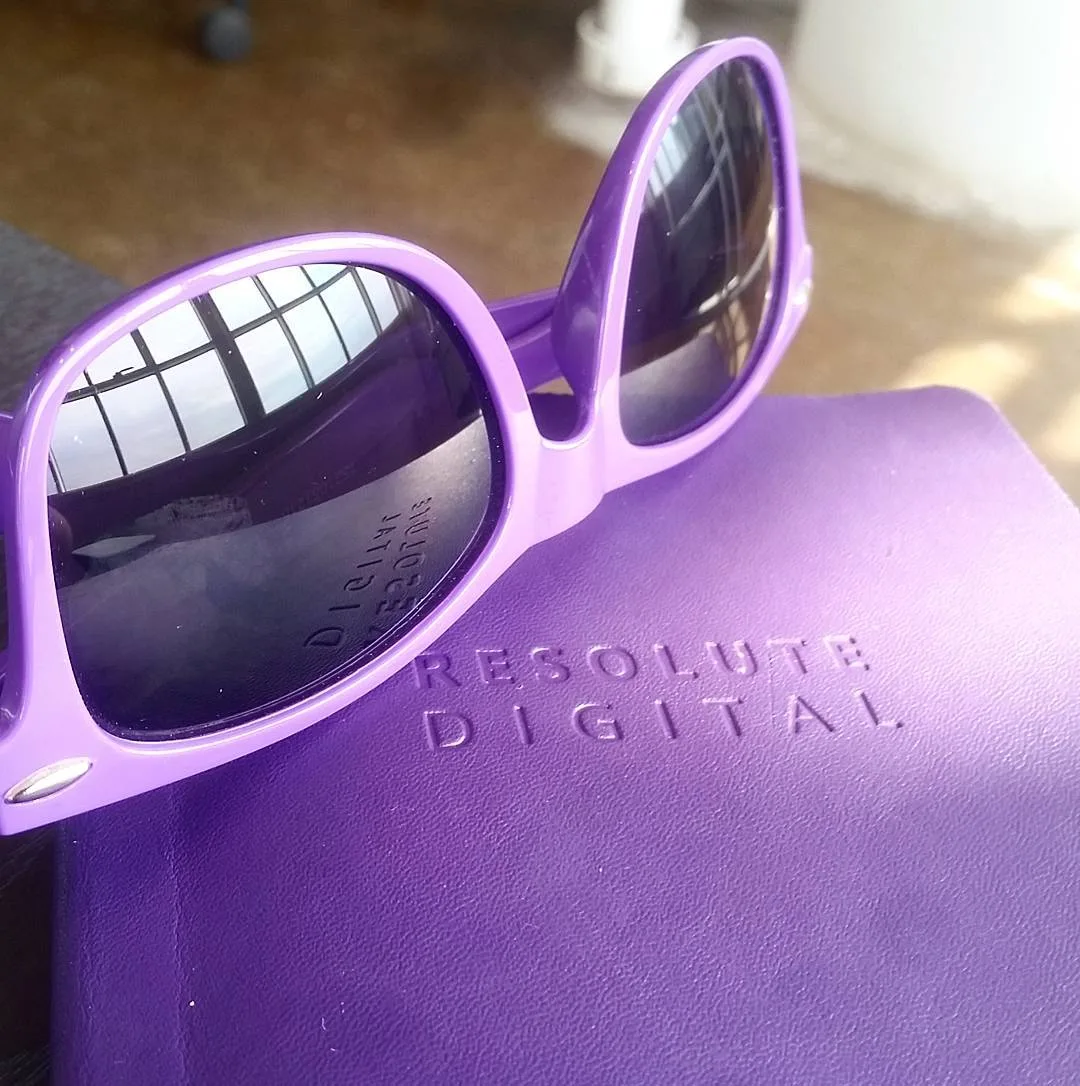 Resolute branded sunglasses resting on purple branded notebook